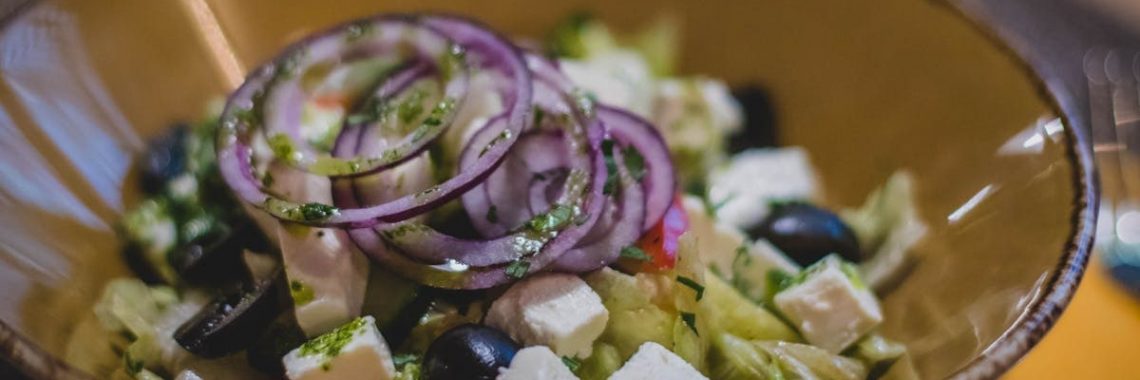 A mouth-watering Greek salad featuring fresh feta, black olives, and red onion rings.